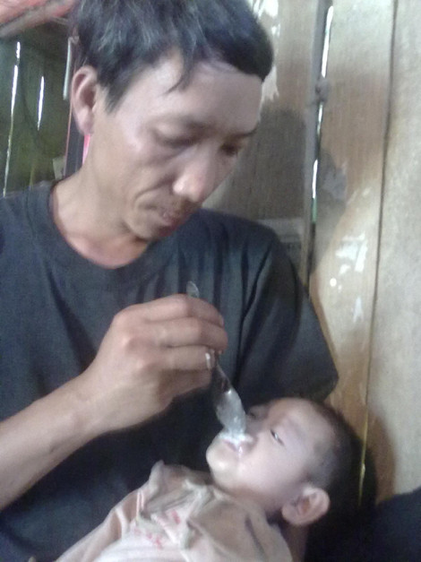Không có gì ăn, anh Quyết đang bón từng thìa cơm trộn bột canh cho bé Tâm.