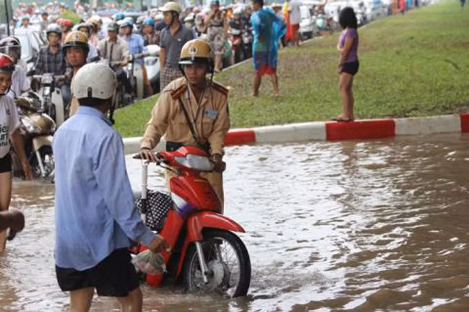 CSGT dắt xe cho người dân đi qua khu ngập lụt. Ảnh: GDVN