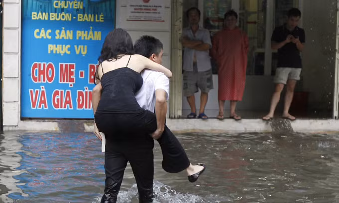 Cô gái được cõng qua khu vực bị ngập nước ở Thủ đô. Ảnh: BBC