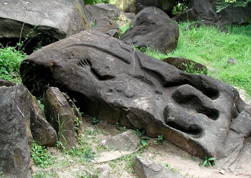 Phía sau ngôi đền là vách núi với những phiến đá nằm rải rác, trên đó những người thợ tài hoa xưa đã tạc những bức tượng lớn nhỏ rất sống động.