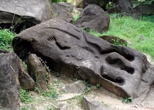 Phía sau ngôi đền là vách núi với những phiến đá nằm rải rác, trên đó những người thợ tài hoa xưa đã tạc những bức tượng lớn nhỏ rất sống động.