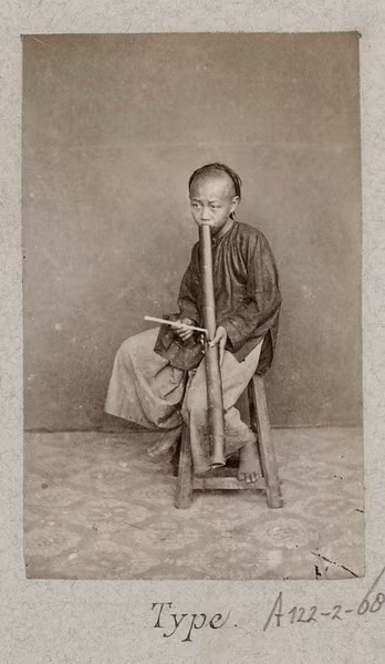 Cậu bé người Hoa hút thuốc bằng ống điếu.
