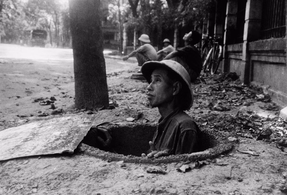 Một người đàn ông trú ẩn trong hố tránh bom trong một đợt báo động ở Hà Nội. Ảnh: Hulton-Deutsch Collection/ CORBIS/ Getty.