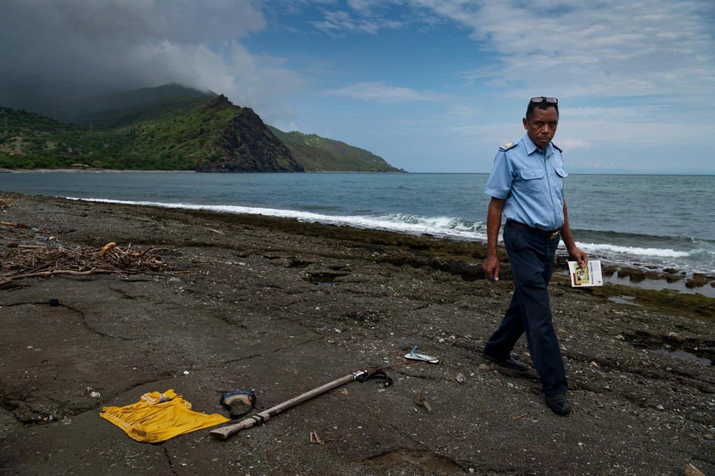 Một sĩ quan cảnh sát kiểm tra đồ đạc của Agostinu da Cunya, 17 tuổi. Cậu bé mất tích kể từ khi đi bắt cá với anh trai mình. Gia đình cho biết cậu bị cá sấu tấn công.