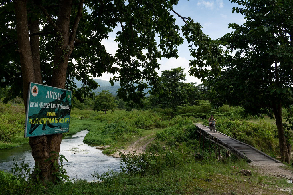 Một tấm biển bằng tiếng Tetum cảnh báo về nguy cơ cá sấu. Các cuộc tấn công cá sấu ở đây đã tăng gấp 20 lần trong thập kỷ qua, với số lượng ít nhất một người chết mỗi tháng tại một quốc gia có 1,2 triệu người.