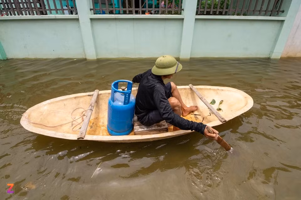 Đang nấu cơm thì hết gas, ông Tuấn người dân xóm Bến Vôi) phải chèo thuyền hơn 1 km đến đầu làng để đổi vì nhân viên giao gas không thể vào làng do nước ngập.