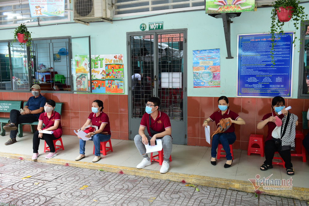 Thầy cô giáo ngồi chờ trước khi được gọi tên để được tiêm vắc xin