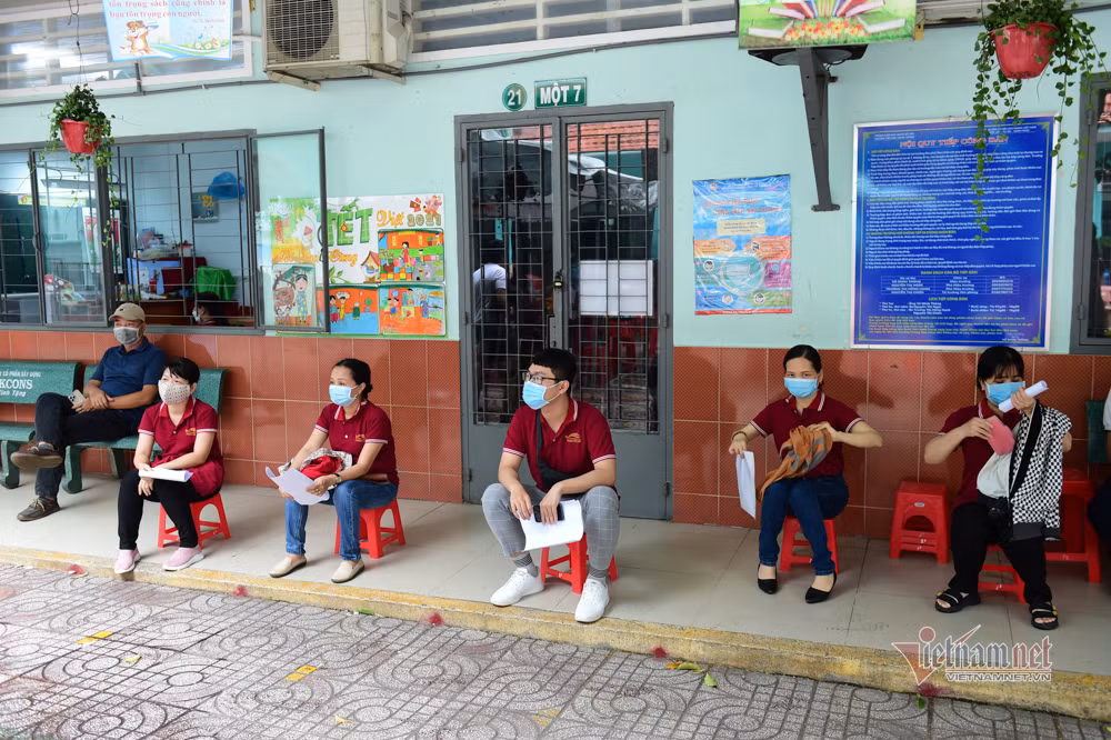 Thầy cô giáo ngồi chờ trước khi được gọi tên để được tiêm vắc xin