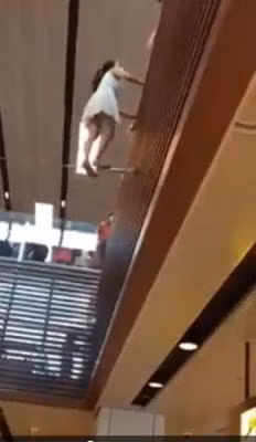 Cô gái "kỳ lạ" đứng vắt vẻo trên một song sắt nhỏ, tìm cách trèo vào trong.