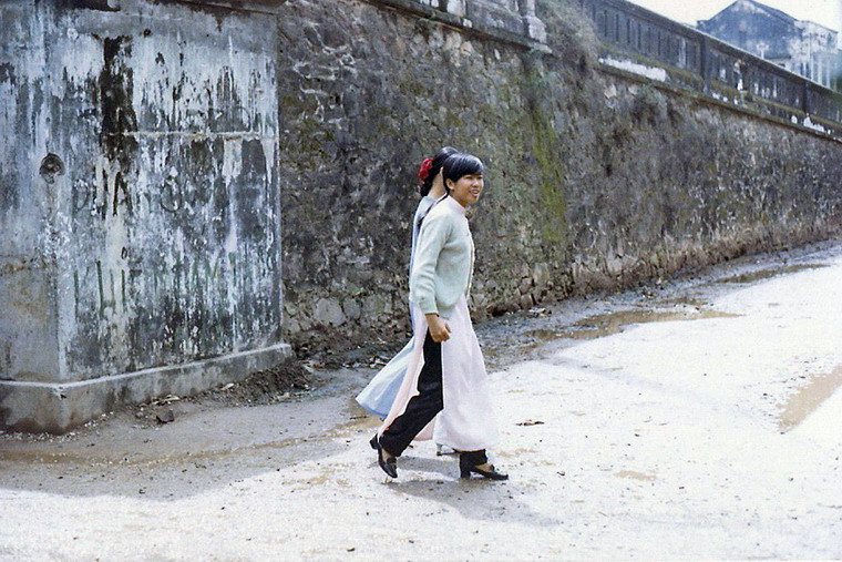 Hai thiếu nữ bước đi cạnh đường dẫn lên cầu Trường Tiền.