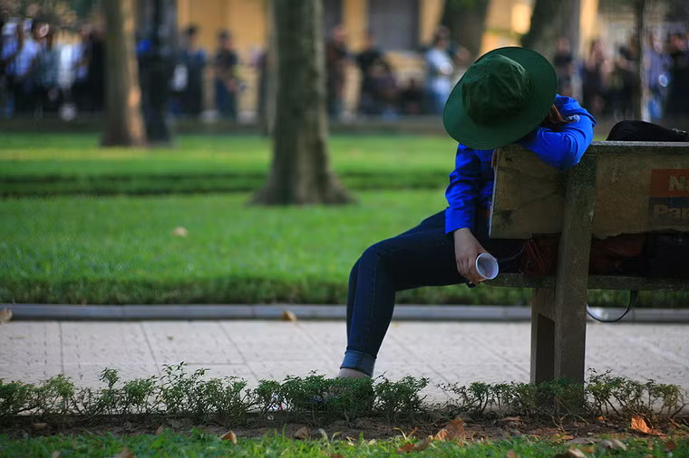 Một thanh niên tình nguyện gục xuống với cốc nước cầm trên tay trong vườn hoa Yersin ngoài nhà tang lễ: một phần vì đau thương, một phần vì mất sức.