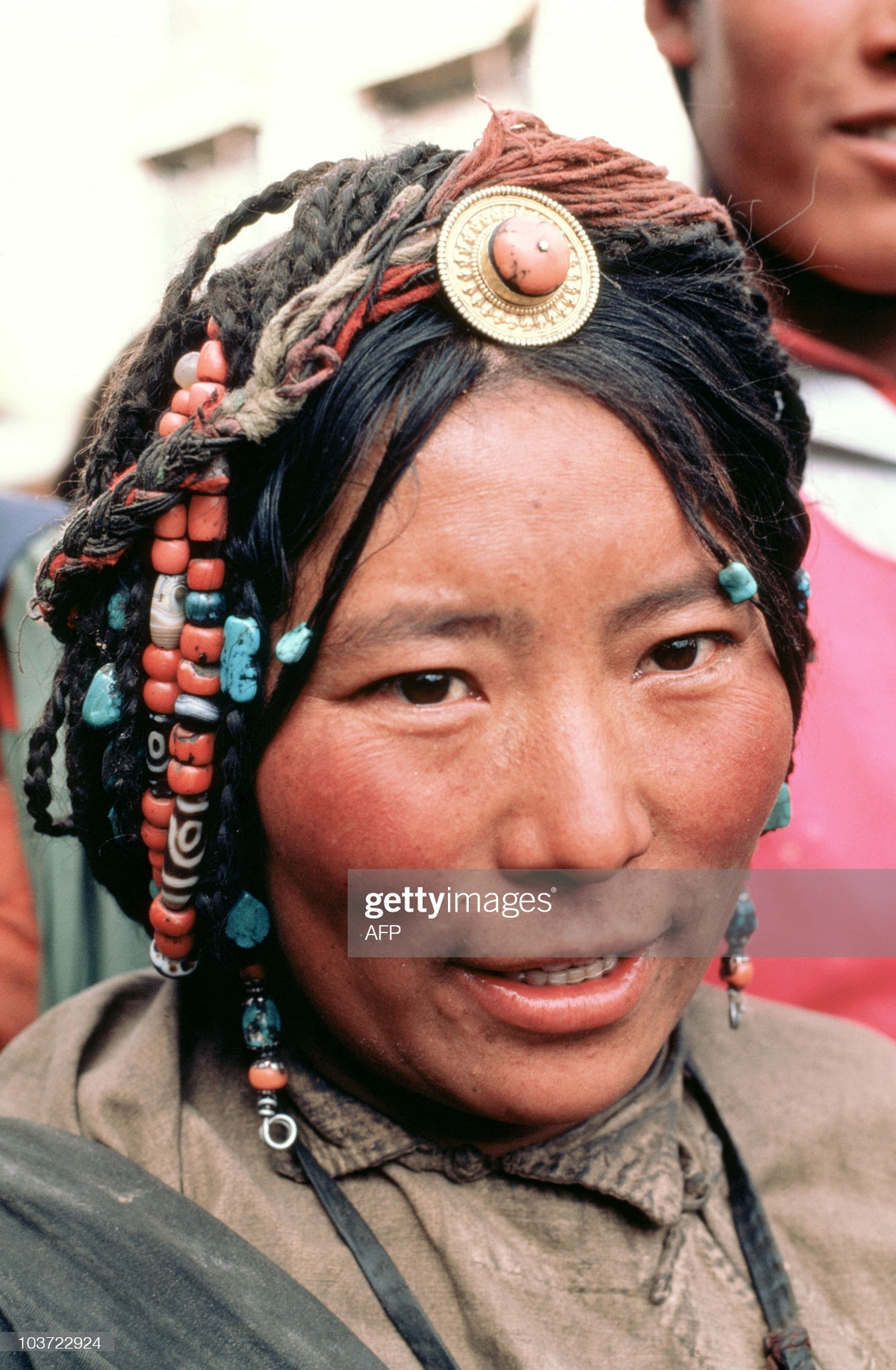 Chân dung một phụ nữ Tây Tạng với mái tóc được trang trí bằng các loại đá tự nhiên nhiều màu sắc.