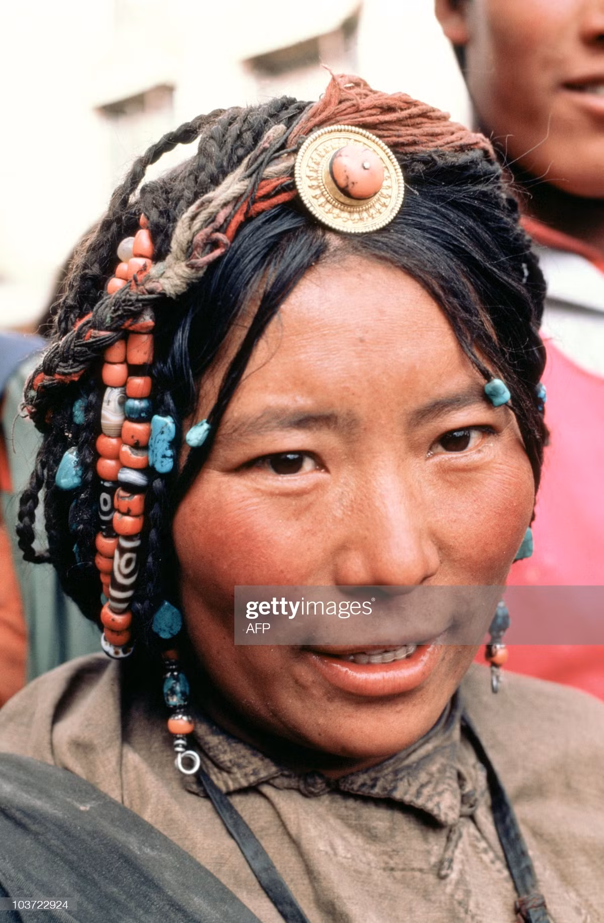 Chân dung một phụ nữ Tây Tạng với mái tóc được trang trí bằng các loại đá tự nhiên nhiều màu sắc.