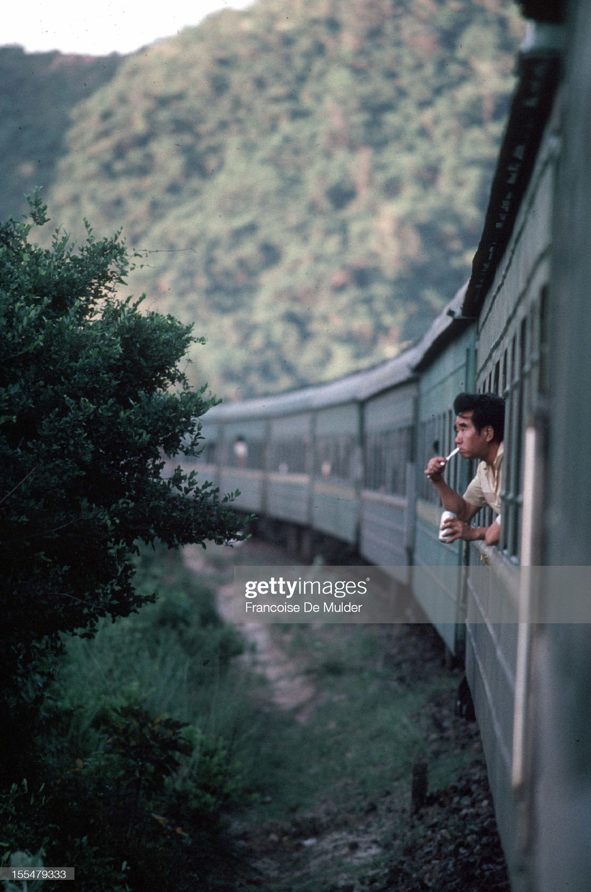 Một người đàn ông nhoài ra cửa sổ để đánh răng khi đoàn tàu đang qua đèo Hải Vân vào lúc sáng sớm, 1989.