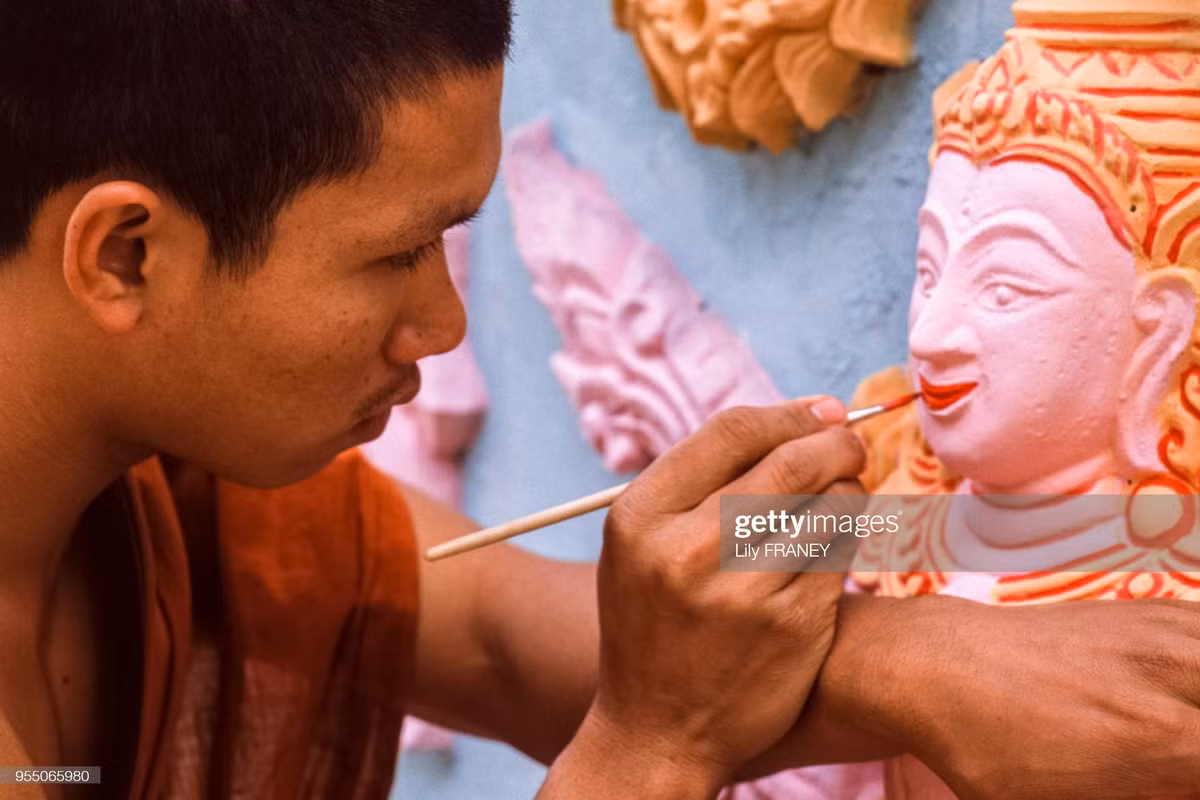 Nhà sư trẻ tô màu cho bức tượng ở chùa.