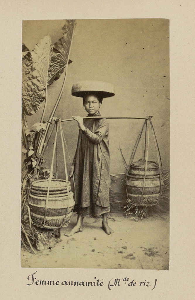 Bé gái Việt Nam với cặp quang gánh trên vai.