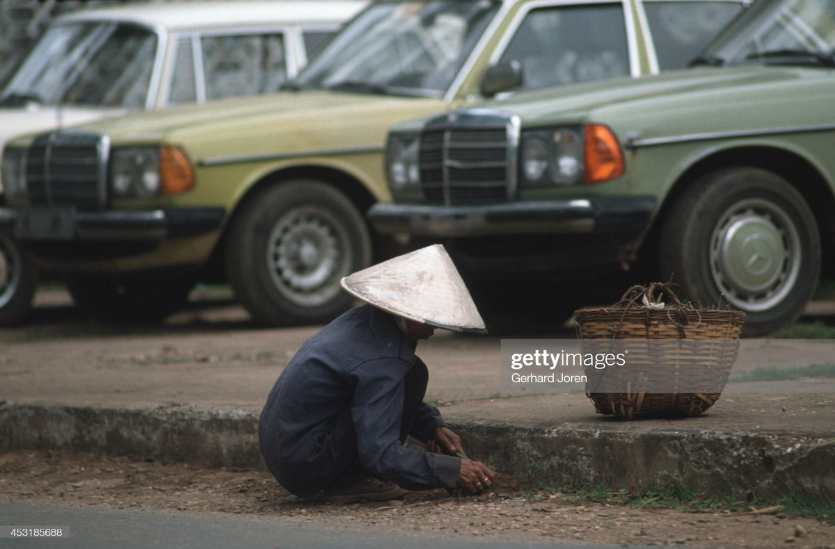 Người nữ lao công nhổ cỏ trên đường phố Vientiane.