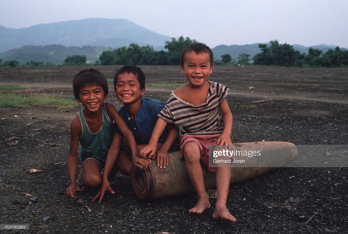 Trẻ em Vang Vieng tươi cười bên quả bom Mỹ sót lại từ thời chiến tranh.