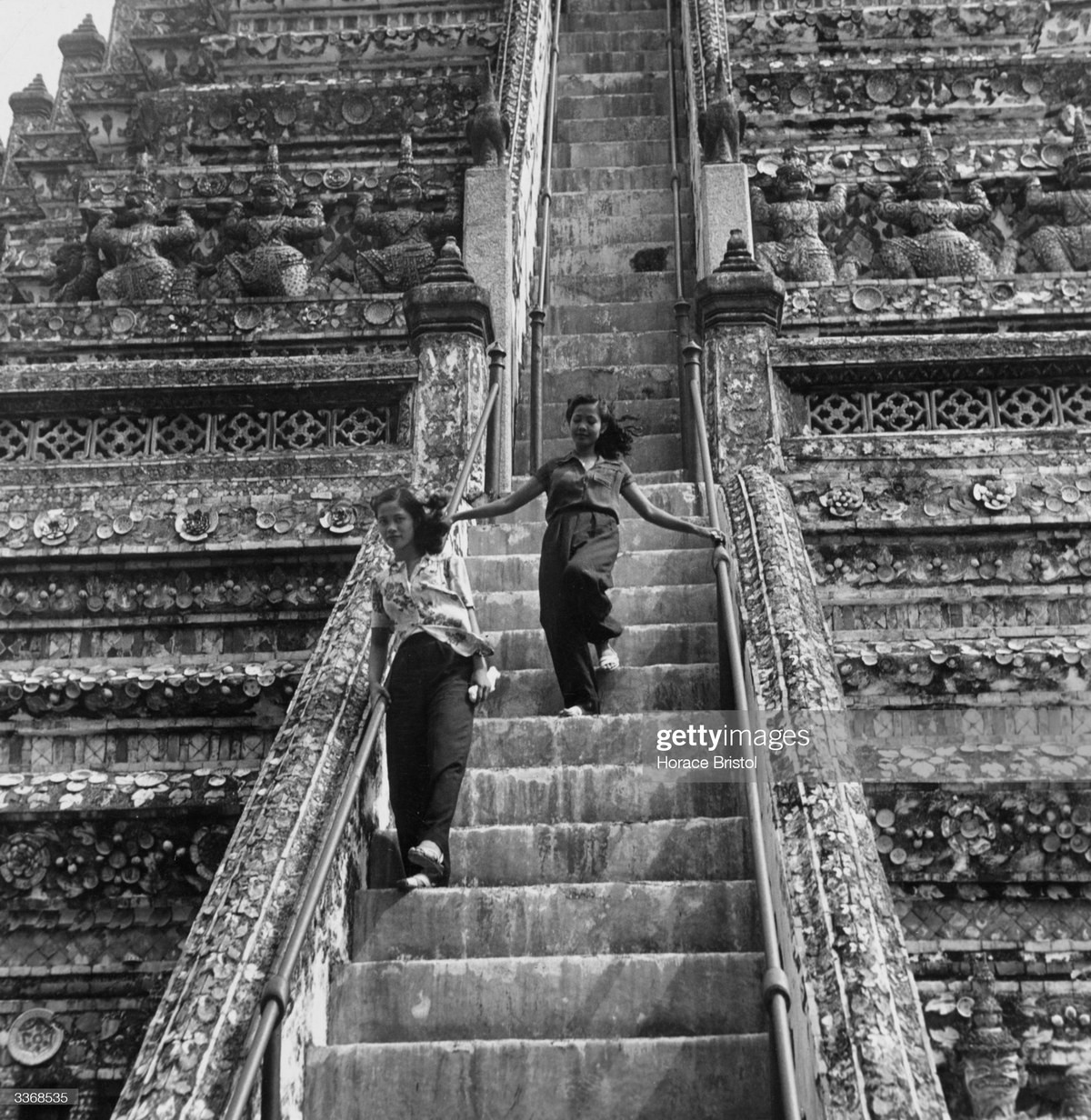 Hai cô gái bước xuống những bậc thang dốc của Wat Arun, một trong những ngôi chùa được trang trí công phu nhất ở Bangkok, khoảng 1955.