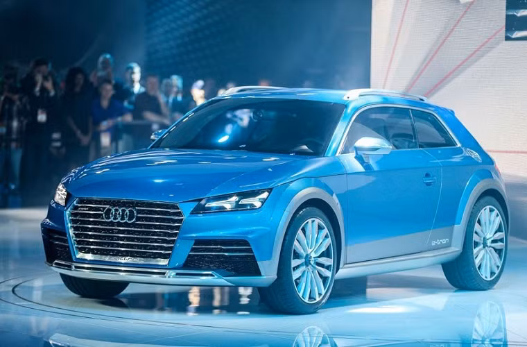 Chiếc SUV Audi E-Tron Quattro hầm hố mạnh mẽ trên bục trưng bày với ánh sáng xanh màu ngọc lục bảo lộng lẫy.