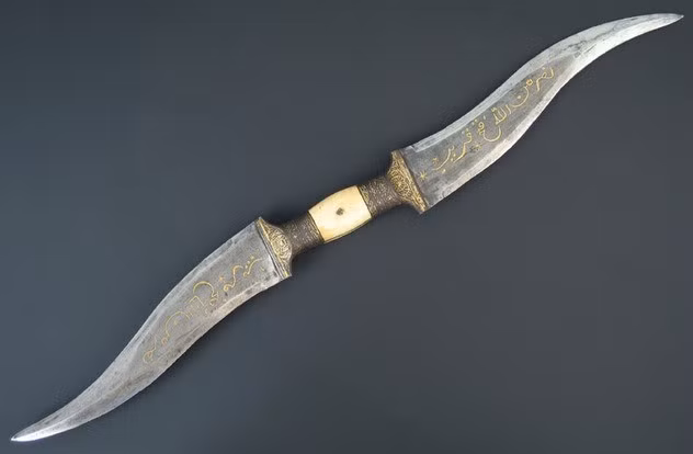 9. Haladie. Haladie là một trong những vũ khí thú vị và đáng sợ nhất đến từ Ấn Độ. Các chiến binh Rajput sử dụng loại dao này để đâm hoặc chém kẻ thù. Haladie có hai lưỡi, được nối với nhau ở giữa bằng tay cầm. Một vài loại còn trang bị cán kim loại cùng đinh nhọn, tạo nên vũ khí 3 lưỡi khủng khiếp. Những chiến binh Ấn Độ chứng tỏ mình là những đối thủ đáng sợ khi họ trang bị cùng lúc Haladie và thanh kiếm nổi tiếng Khanda.