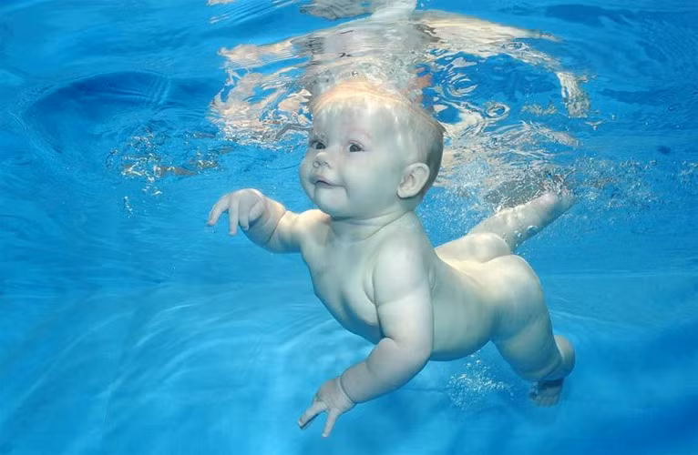 Dạy con cách đạp chân. Hãy khuyến khích bé đạp chân và càng tung nhiều bọt càng tốt. Bạn có thể tạo ra một trò chơi từ hoạt động này. Khi đã có những kỹ năng căn bản về chân, hãy dạy con động tác quạt tay dưới nước và những động tác khác.