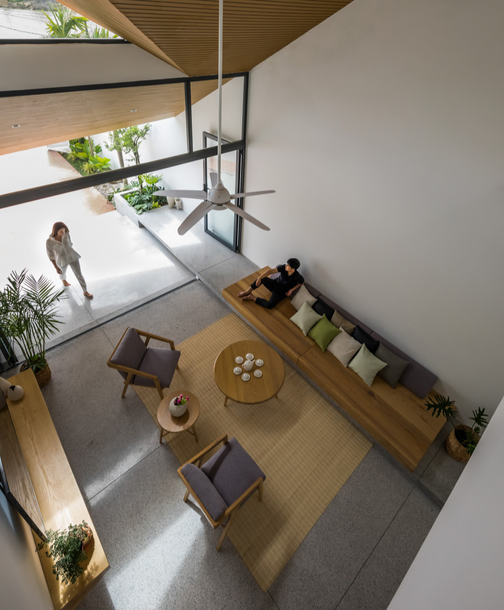 Phòng khách được kết nối với tầng trên bằng khoảng không gian thông tầng lớn. Không gian bắt đầu đóng dần khi giảm cao độ trần ở phòng ăn và đóng hẹp lại khi qua hành lang kết nối ra phía sau nhà. Từ hành lang đó lại mở rộng, kết nối bếp, giếng trời và phòng ngủ của bố mẹ.