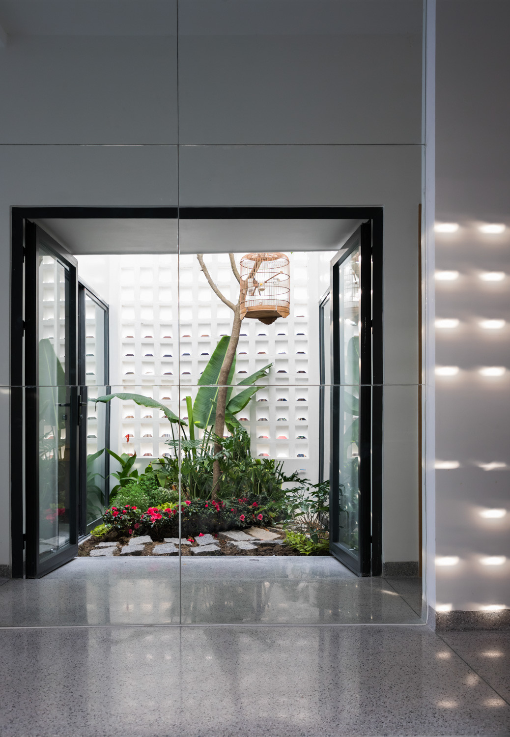 Phòng ngủ bố mẹ được bố trí tách biệt với không gian phòng khách, phòng ăn, bếp bằng giếng trời có khu vườn nhỏ giữa nhà. Phòng 2 con được bố trí trên tầng 2, cũng kết nối với nhau qua giếng trời này.