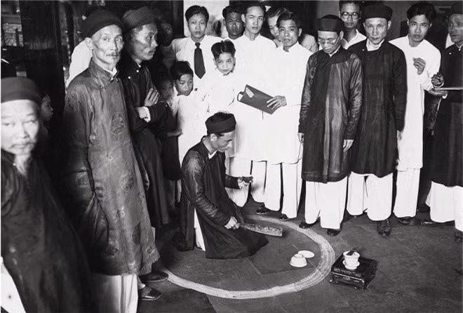 Đền Bạch Mã ở Hà Nội, tháng 4/1936. Đền thờ thần Bạch Mã (Ngựa trắng) và thờ thần Long Đỗ. Ngôi đền này cũng là nơi thường diễn ra các nghi lễ uống máu ăn thề. Trong ảnh, người chủ nợ đang ngồi đợi trong vòng vôi.