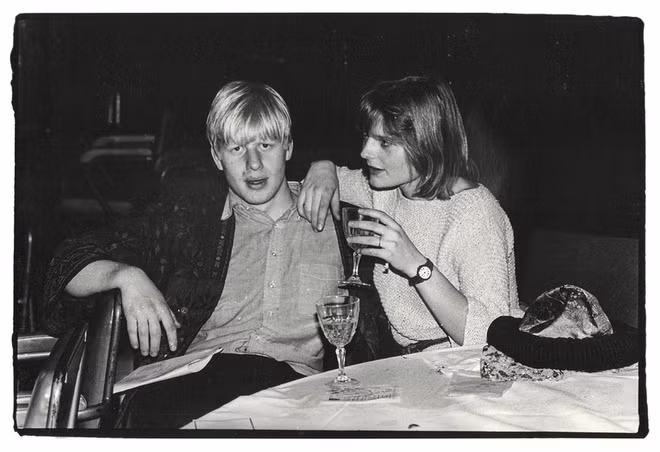 Trong đó, nhiếp ảnh gia Dafydd Jones đã chụp được hình ảnh Boris Johnson, 21 tuổi, đang ngồi cạnh người vợ đầu tiên trong tương lai. Dáng ngồi của Thủ tướng Anh thời điểm đó dường như hơi kỳ lạ và không thoải mái. Ảnh: Dafydd Jones.