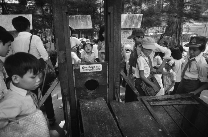 Các em học sinh bên chiếc máy chém chính quyền Ngô Đình Diệm sử dụng ở miền Nam Việt Nam đầu thập niên 1960, trưng bày ở bảo tàng Chứng tích chiến tranh, TP HCM.