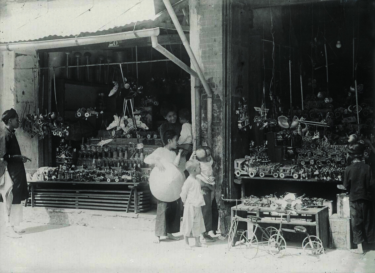 Trẻ em tại một cửa hàng đồ chơi ở Hà Nội thập niên 1920. Có hai chiếc xe đạp trẻ em đóng bằng sắt (phía dưới, bên phải), một món đồ chơi "xa xỉ" của trẻ em thời đó.