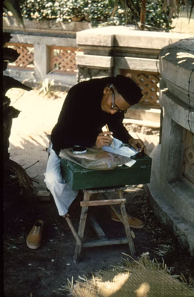 Với bút lông và mực tàu, ông thầy này đang chăm chú đoán mệnh, giải quẻ, 1956.