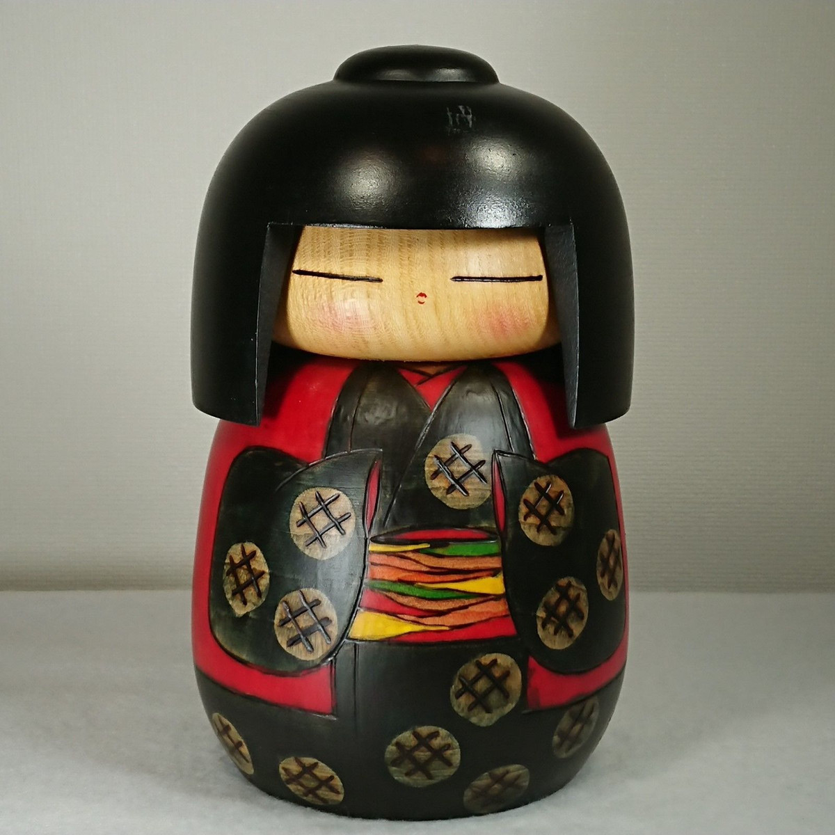 Phần thân Kokeshi được tô họa tiết bằng sơn, thường là màu đỏ và đen, sau đó được phủ lên một lớp sáp bóng. Mặt đáy búp bê được đánh dấu bằng chữ ký của người làm.