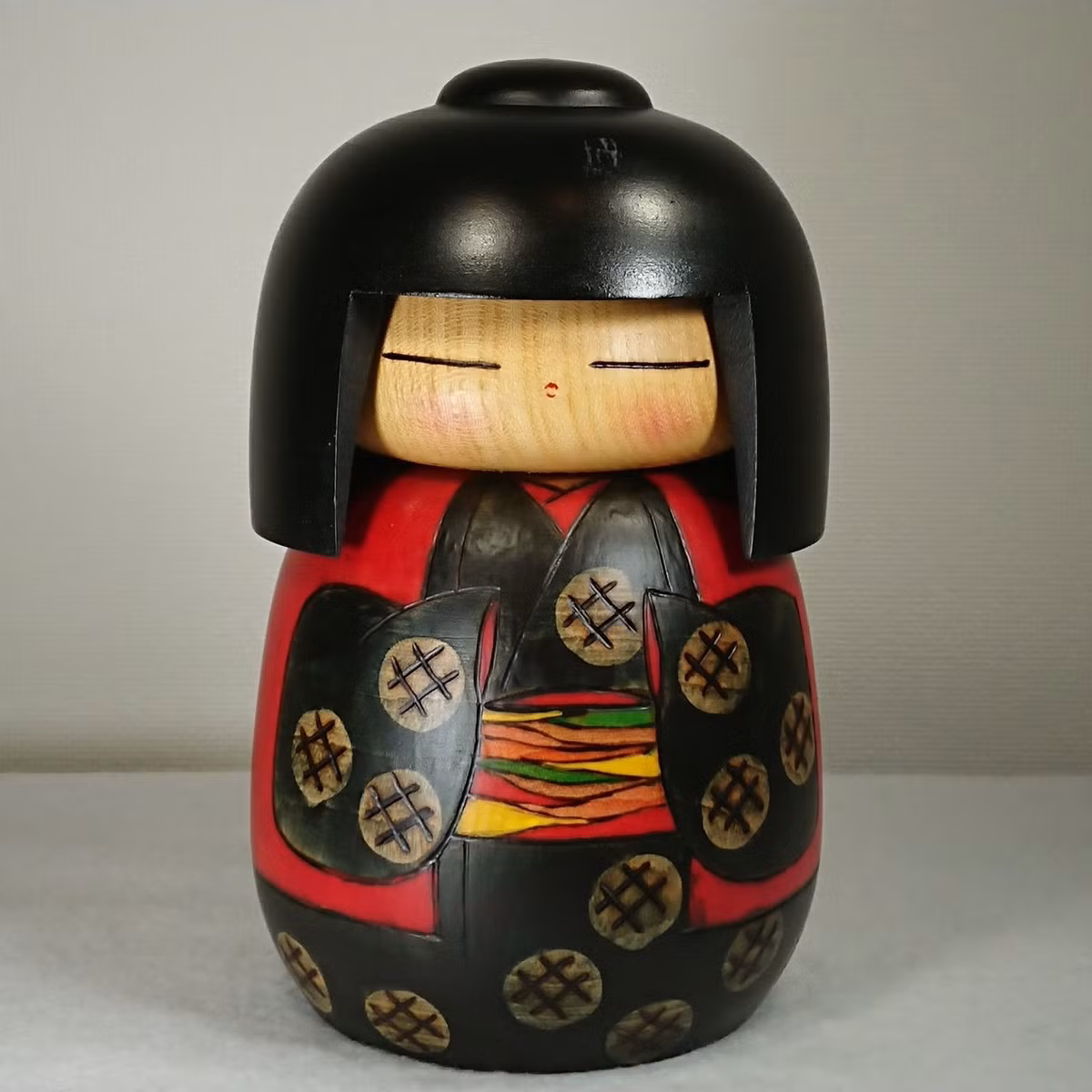 Phần thân Kokeshi được tô họa tiết bằng sơn, thường là màu đỏ và đen, sau đó được phủ lên một lớp sáp bóng. Mặt đáy búp bê được đánh dấu bằng chữ ký của người làm.