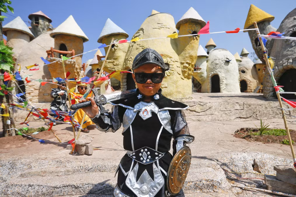 Cư dân vương quốc người lùn Qiangyong chụp ảnh bên ngoài những ngôi nhà được thiết kế như trong truyện cổ tích trong công viên theo chủ đề vương quốc người lùn ở Côn Minh.