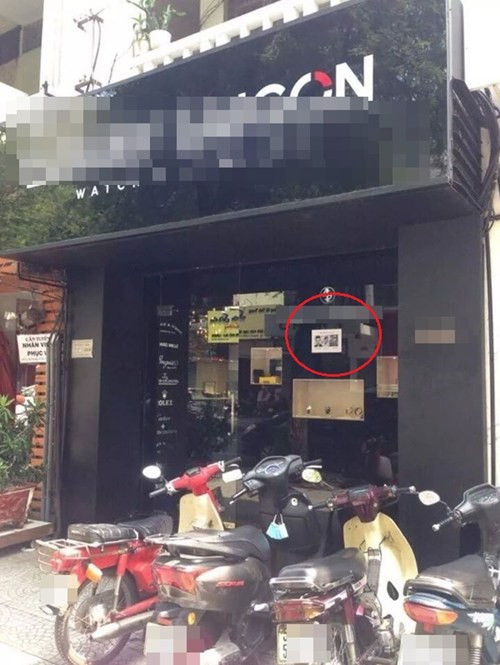 Tấm biển được đặt trước cửa hàng, nơi công cộng, có nhiều người qua lại.