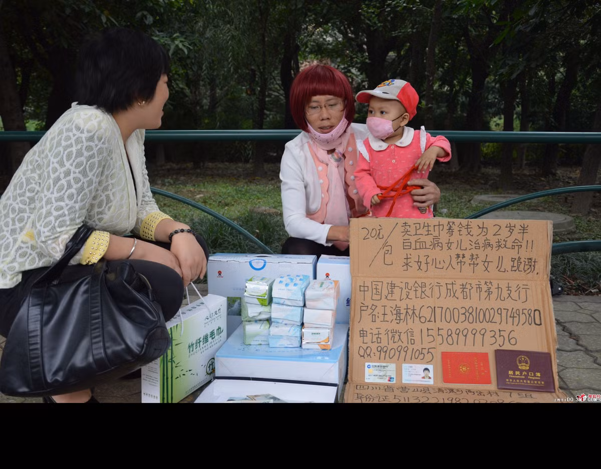 Ngày 8/10 vừa qua, cộng đồng Trung Quốc xôn xao trước những bức ảnh chụp một người “phụ nữ” ngồi lề đường bán băng vệ sinh với tấm bảng xin mọi người ủng hộ để có tiền chữa bệnh bạch cầu cho con gái.