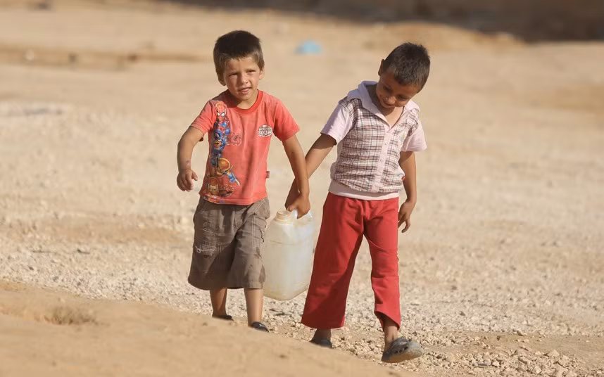 Hai cậu bé người Syria xách nước về lều của gia đình mình.