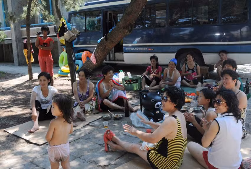 Mọi người ngồi nghỉ dưới bóng cây sau khi tắm biển.