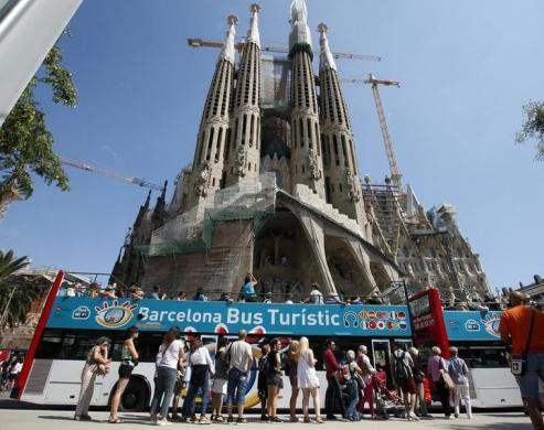 Mọi người đứng xếp hàng chờ lên xe bus trước nhà thờ cổ nổi tiếng Basilica Sagrada Familia ở Barcelona.