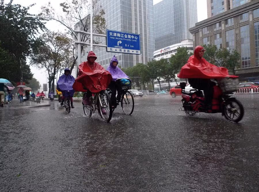 Mọi người di chuyển dưới mưa trên đường phố ở Thiên Tân.