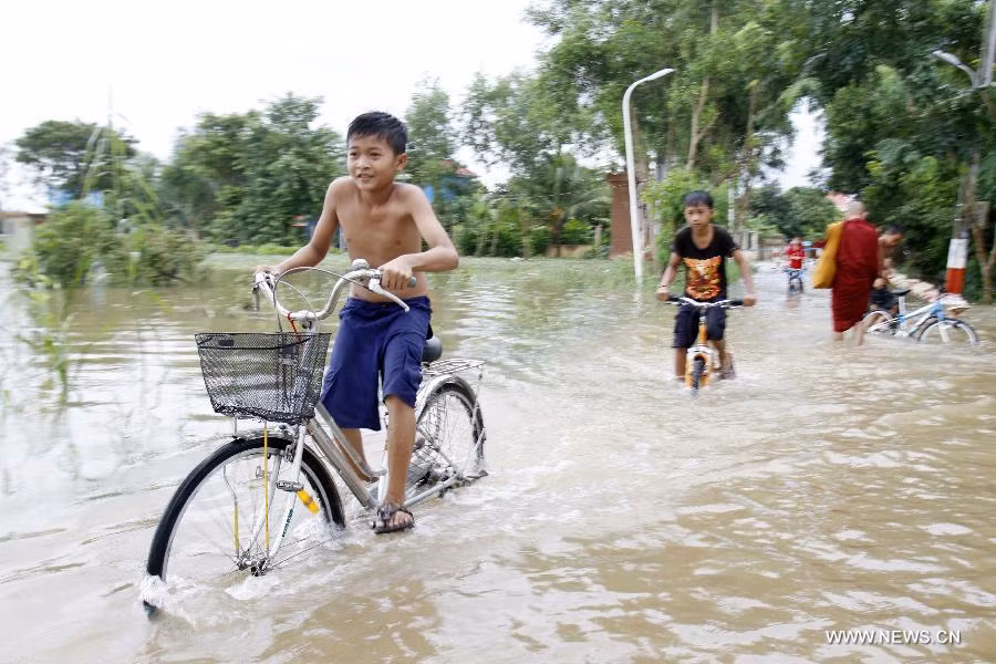 Các cậu bé tỏ ra thích thú đạp xe trên đường ngập nước.