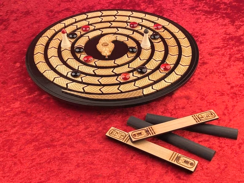  9. Mehen trong văn hóa trò chơi. Trong một số phiên bản của trò chơi Senet (trò chơi cờ nổi tiếng của Ai Cập cổ), Mehen được sử dụng như một hình ảnh tượng trưng cho sự bảo vệ trong những vòng chơi, nơi người chơi phải vượt qua các thế lực xấu và đạt được sự tái sinh. Ảnh: Pinterest.