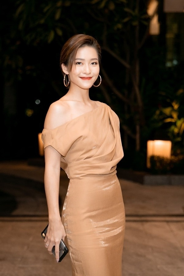 Dự đám cưới Thúy Vân, Khả Ngân nổi bật khi diện đầm màu nude ánh đồng sang chảnh thanh lịch. Thiết kế lệch vai giúp cô nàng khoe khéo bờ vai trần mảnh mai.