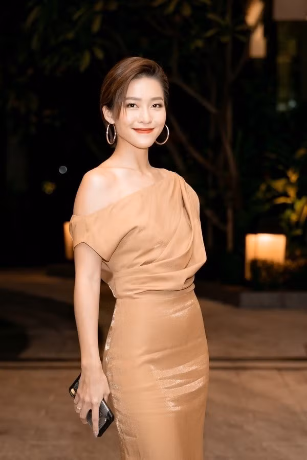 Dự đám cưới Thúy Vân, Khả Ngân nổi bật khi diện đầm màu nude ánh đồng sang chảnh thanh lịch. Thiết kế lệch vai giúp cô nàng khoe khéo bờ vai trần mảnh mai.