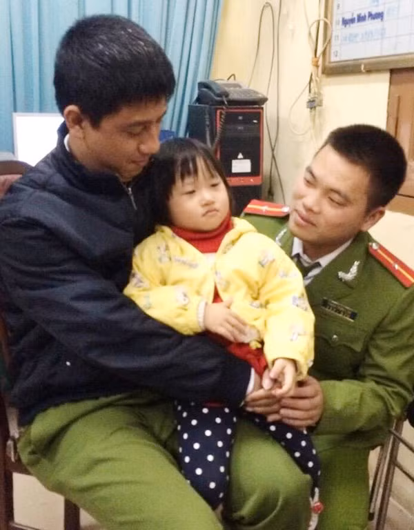 Bé Hằng trong trong vòng tay các chiến sĩ cảnh sát sau khi được giải cứu.