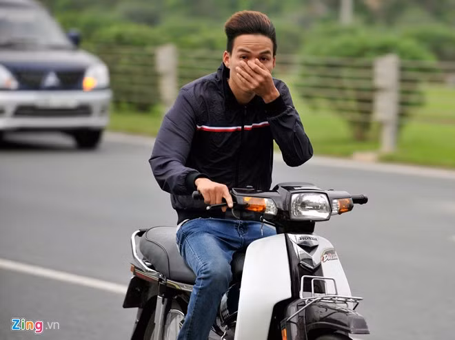 Nam thanh niên không đội mũ bảo hiểm vội vàng che mặt khi bị chụp ảnh đi vào làn ôtô với tốc độ cao.