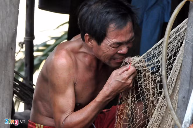 Khi con nước xuống cũng là lúc những ngư dân nơi đây lại tất bật đi chèo thuyền mang lưới, chài vươn ra sông để mưu sinh. Những lúc nước lớn họ nghỉ ngơi trong sự bình yên, tranh thủ vá lại chài, lưới. Anh Nguyễn Văn Chứng tranh thủ vá lại chiếc chài bị rách trong khi chờ nước xuống.