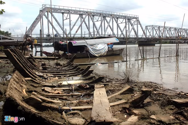 Theo cụ Ngô Thị Liêm, 82 tuổi, cư dân nhiều tuổi nhất, xóm chài hình thành cách đây 38 năm. Trước đó, cụ và một số người từ Vĩnh Phú vào miền Nam năm 1954, miền đất mới đưa họ đến xóm Mới (nay là đoạn thuộc sông Vàm Thuật, phường An Phú Đông, quận 12) hành nghề “đâm hà bá”. Sau giải phóng năm 1975, họ bắt đầu chuyển về tại khu vực bên cầu Bình Lợi để neo đậu và làm nghề đánh cá cho tới nay. Được biết, ngày trước xóm chài khá đông đúc nhưng giờ nhiều hộ có điều kiện đã lên bờ thuê nhà trọ sống. Xóm chài chỉ còn lại 3 hộ gia đình, vỏn vẹn chỉ 8 người. Điều đặc biệt là họ cùng quê, có họ hàng thân thiết với nhau. Trong ảnh: Chiếc ghe gia đình bà Liêm dùng để ở và đánh cá mấy chục năm trước bị hư hỏng, đã nhiều lần sửa chữa và bị chìm nên gia đình bà đành bỏ lại nằm trơ xương trên bãi bồi.